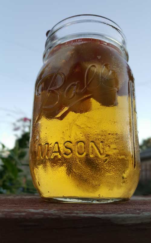 Looking up at a mason jar filled with Autumn Hard Apple Cider Sangria and chopped apples.