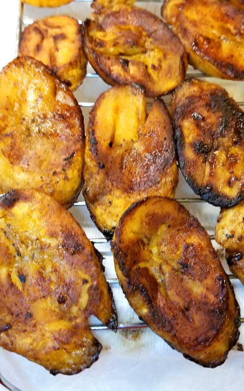 Prepared Sweet Fried Plantains resting on a wire rack to drain their oil.