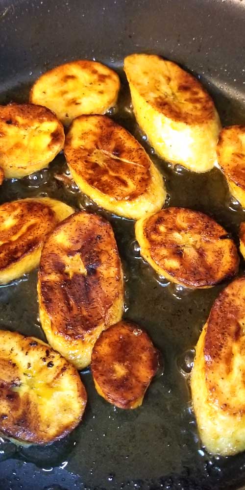 Slices of Sweet Fried Plantains being fried in a non-stick skillet.