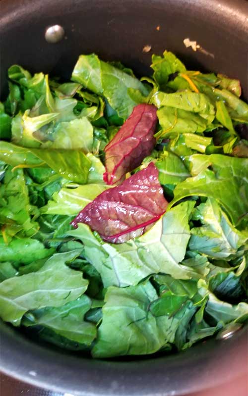 Torn collard greens in a black pot.