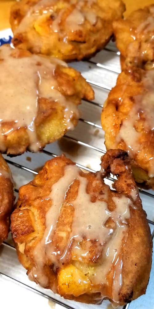 Peach Fritters covered with a with Honey Cinnamon Glaze cooling on a wire rack.
