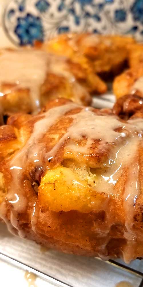 Very close up view of a Peach Fritter showing the Honey Cinnamon Glaze running off the edges, and an exposed piece of peach.