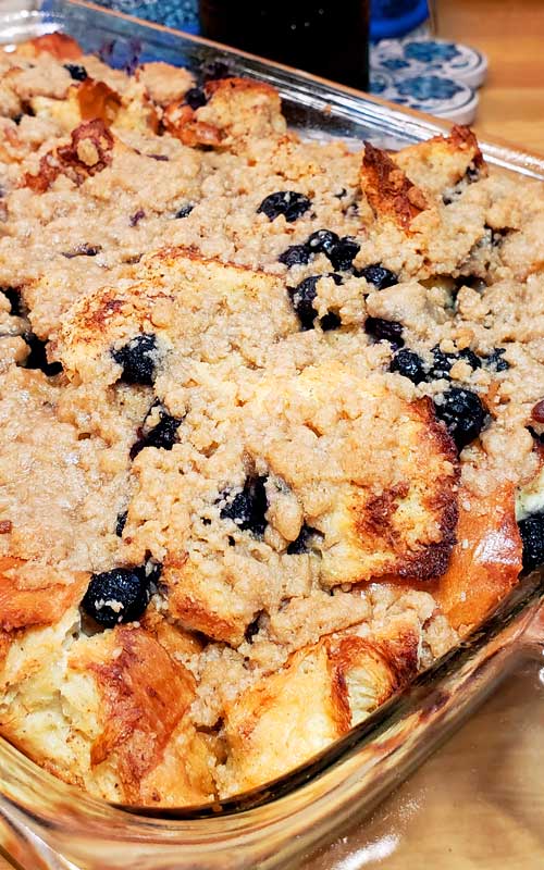 A clear glass baking dish filled with a baked Easy Blueberry French Toast Casserole with Streusel Topping.
