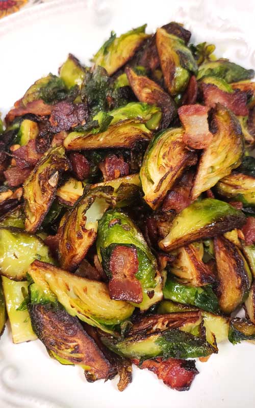 Crispy Skillet Brussels Sprouts with Bacon & Garlic Butter piled up on a white platter.