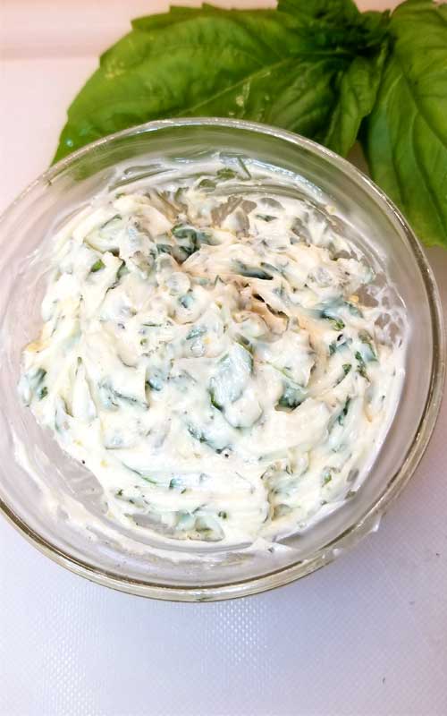 A clear glass bowl filled with a prepared Roasted Garlic Herb Butter.