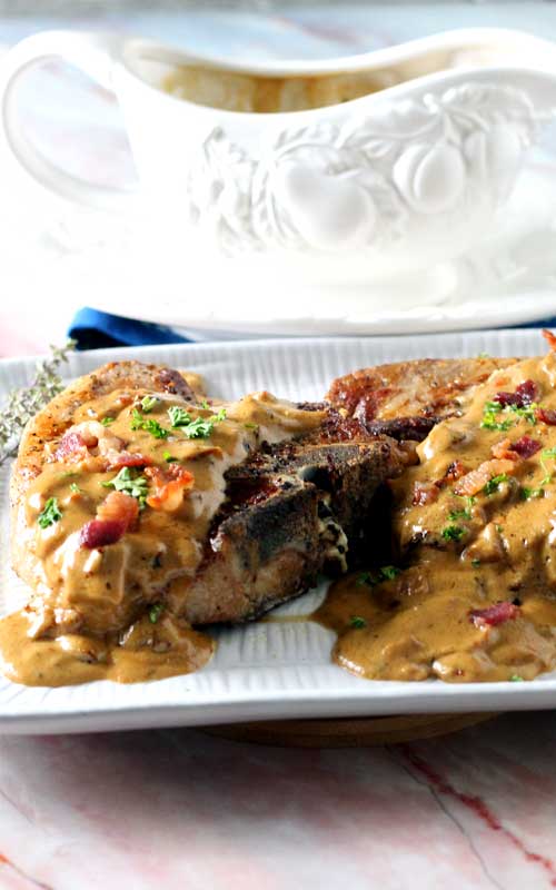 Bacon Gravy Smothered Pork Chops are just the comfort food we needed right about now! Take an everyday pork chop dinner to a whole other level of yum!