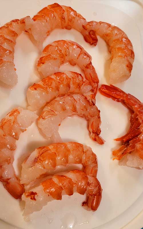 Ten uncooked "Royal Red" shrimp on a white plate.